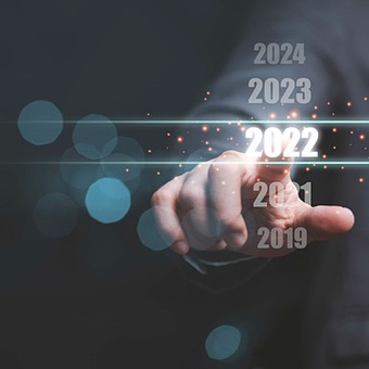 Business man touching a screen image of  the number 2022, with two years prior and two subsequent years also visible.